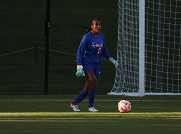 Virginia women's soccer goalkeeper surveys with the ball.